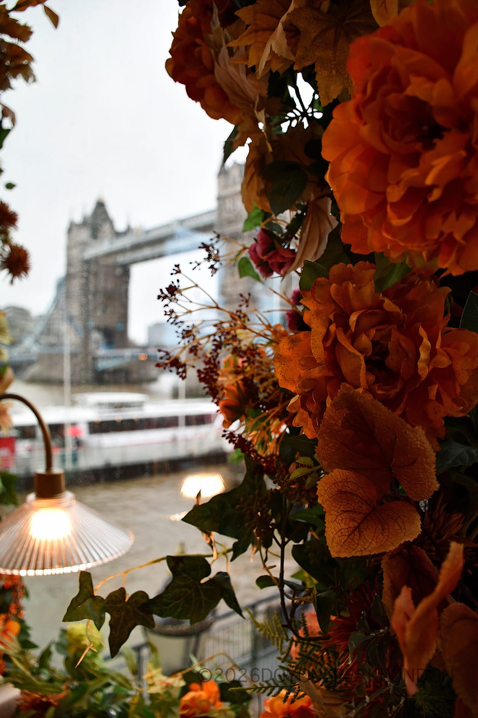 Autumn flowers and a lamp framing Tower Bridge at VU from The Tower
